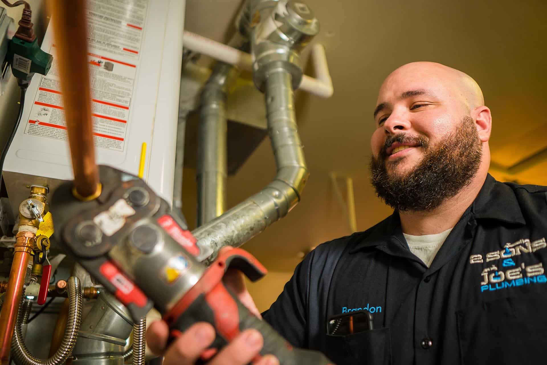 2 Sons technician press-fitting a copper line on a Seattle water heater install