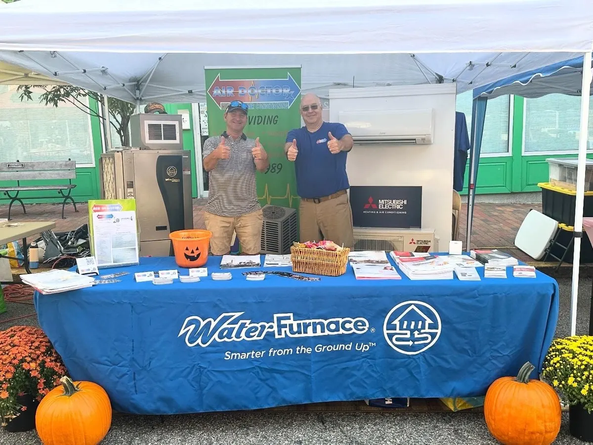 Two of the Air Doctorx crew at the company booth, Milford Freedom Festival, with a geothermal unit and ductless mini-split on display