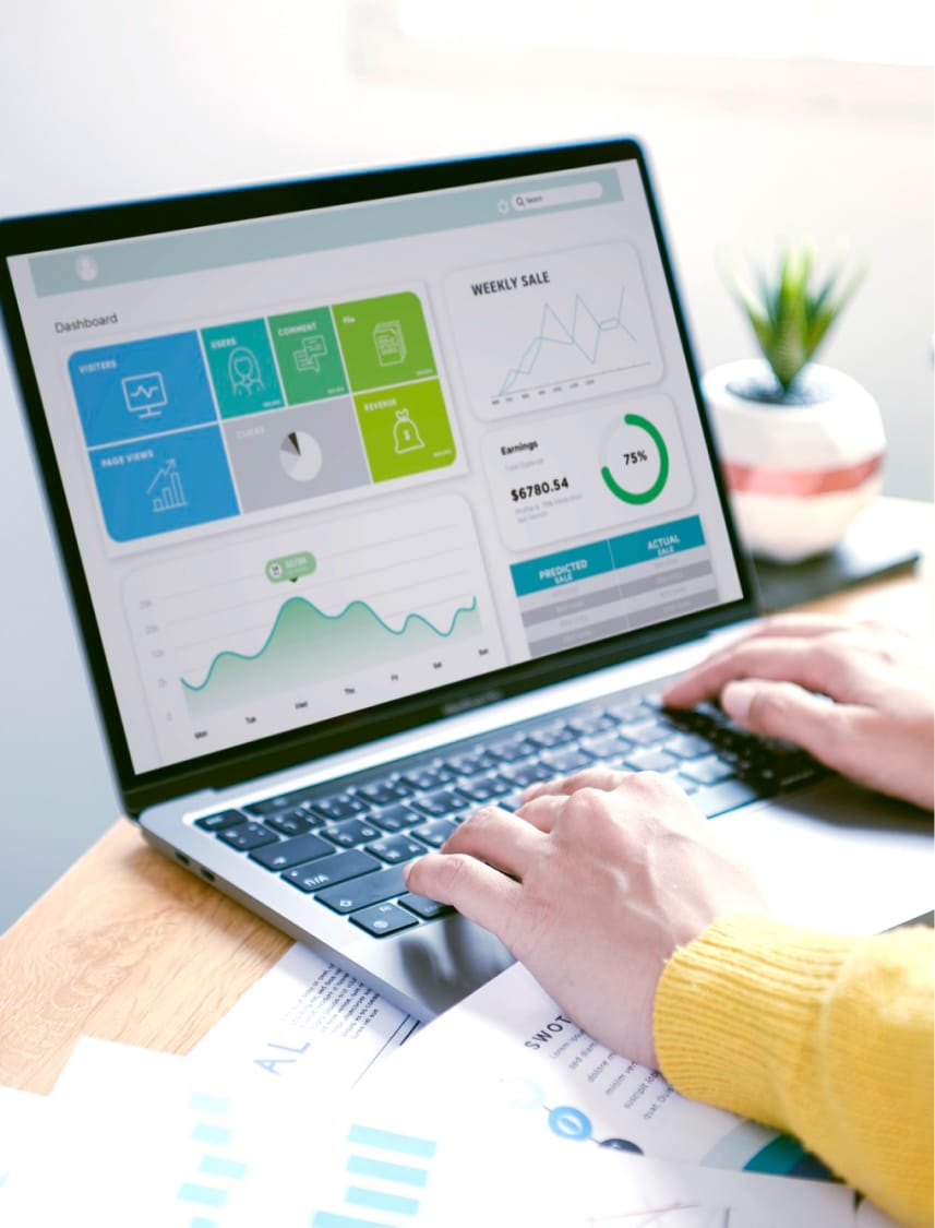 Hands typing on a laptop displaying a colourful marketing analytics dashboard