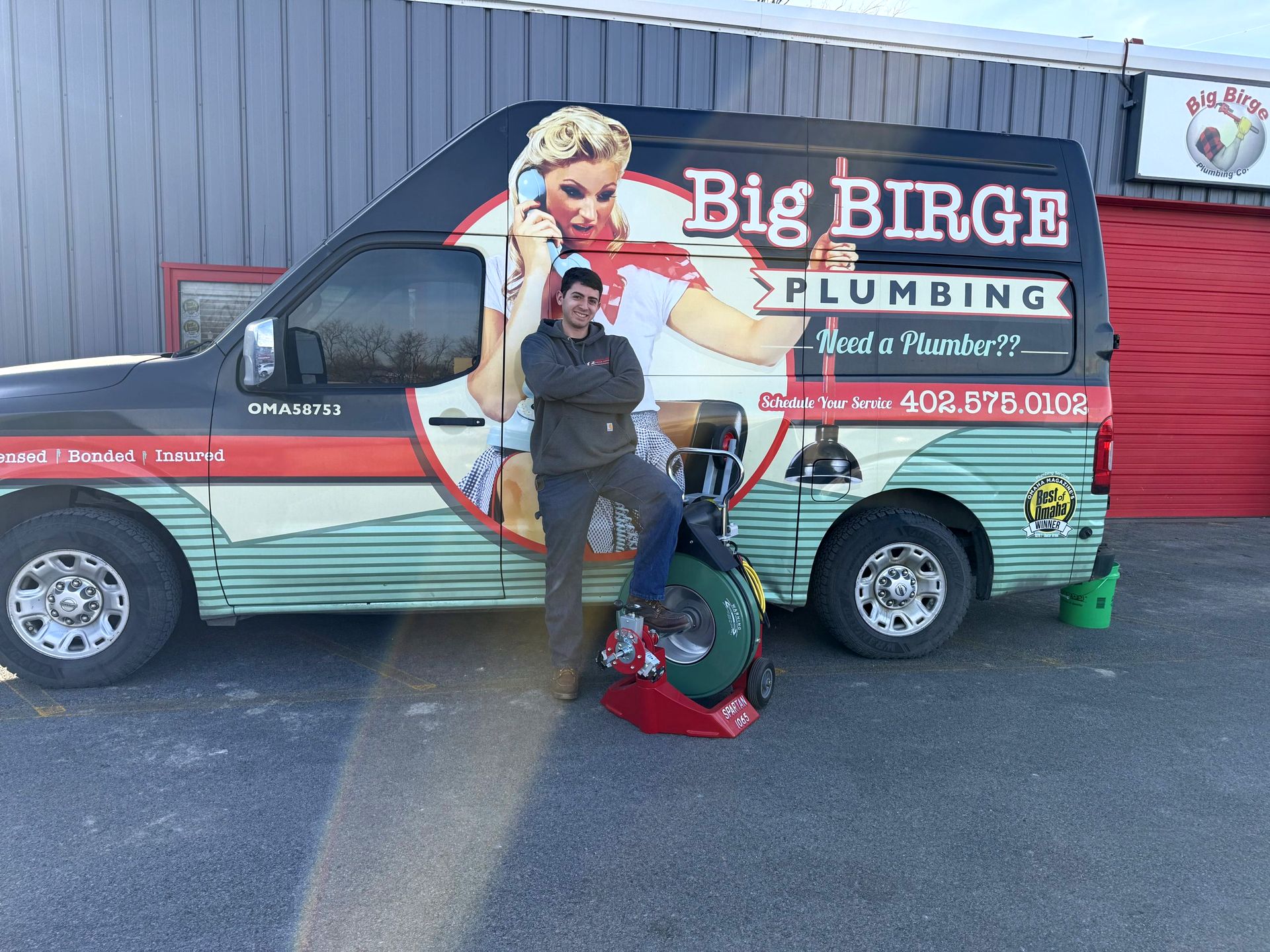 A Big Birge plumber with a drain machine in front of the retro Big Birge Plumbing van in Omaha