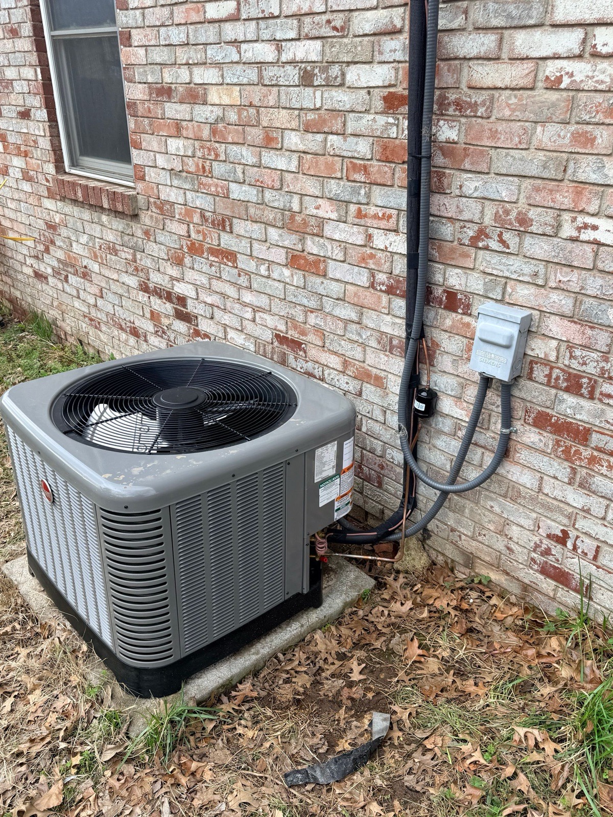 Rheem condenser installed against a painted brick home