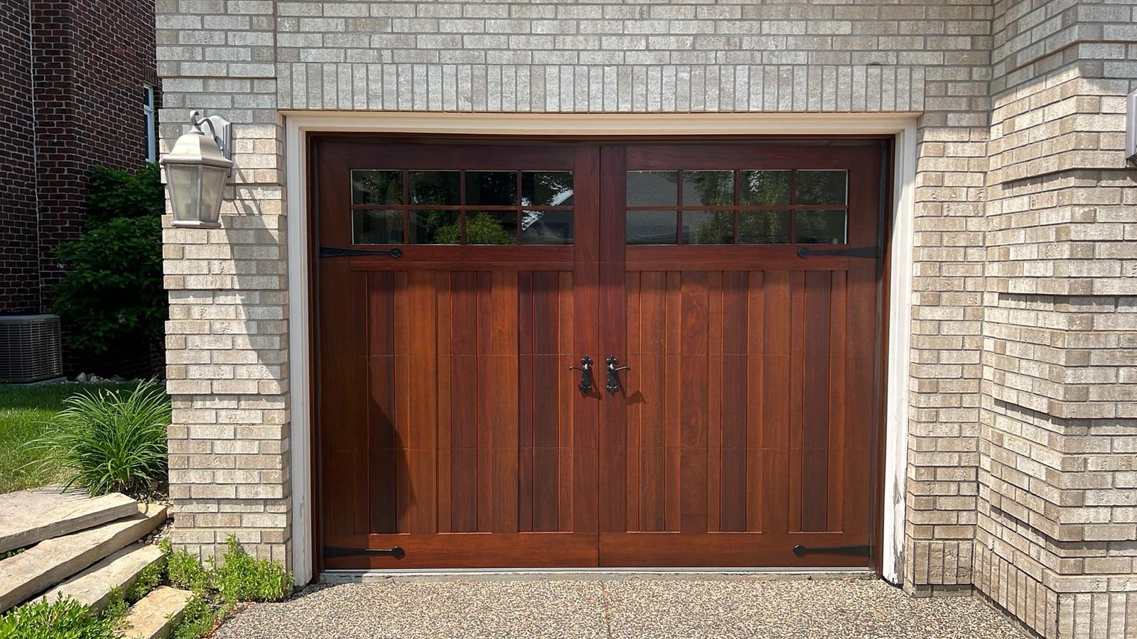 Carriage-style wood garage door installed on a brick home