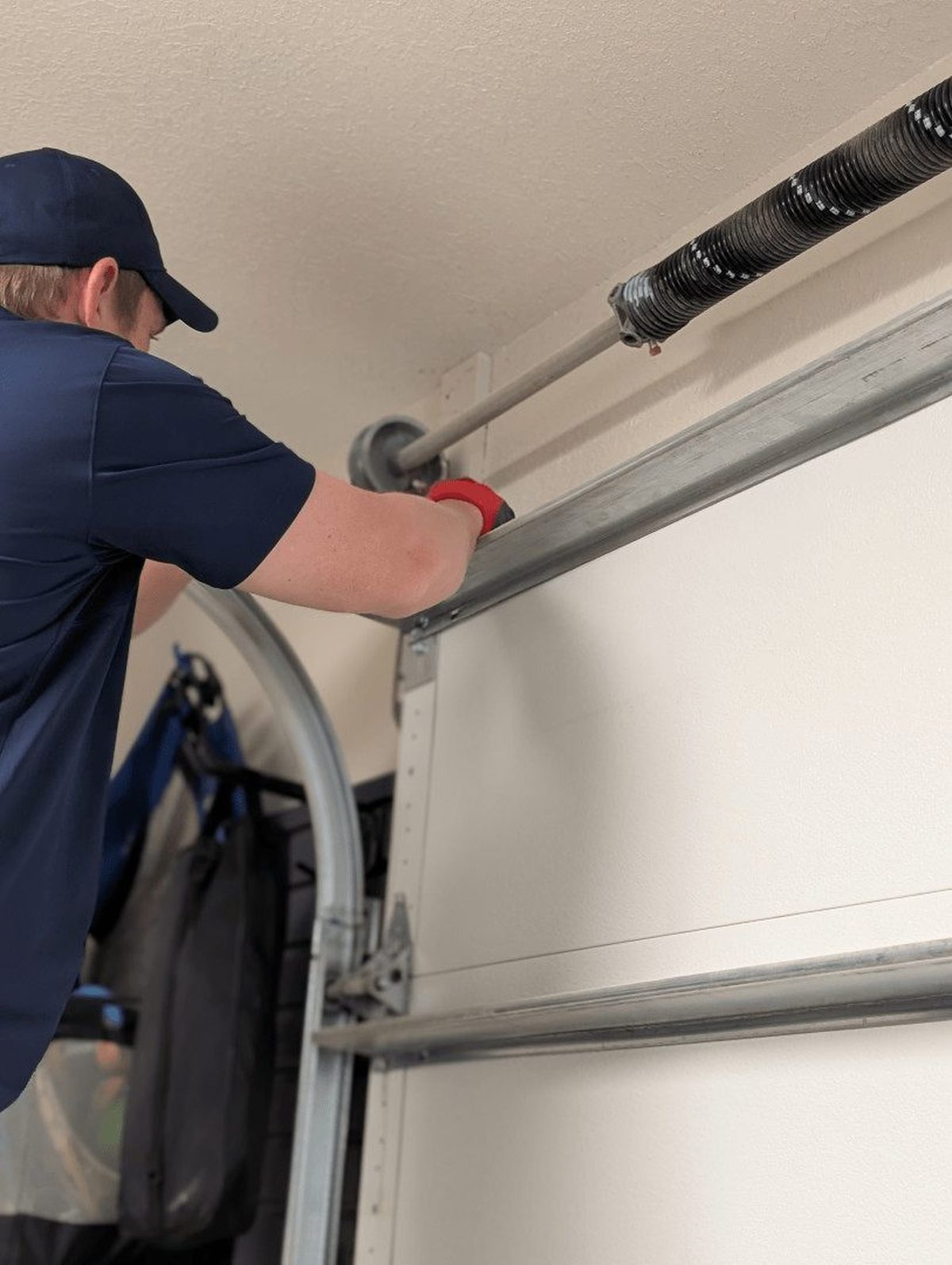 Howdy technician replacing a broken garage door torsion spring