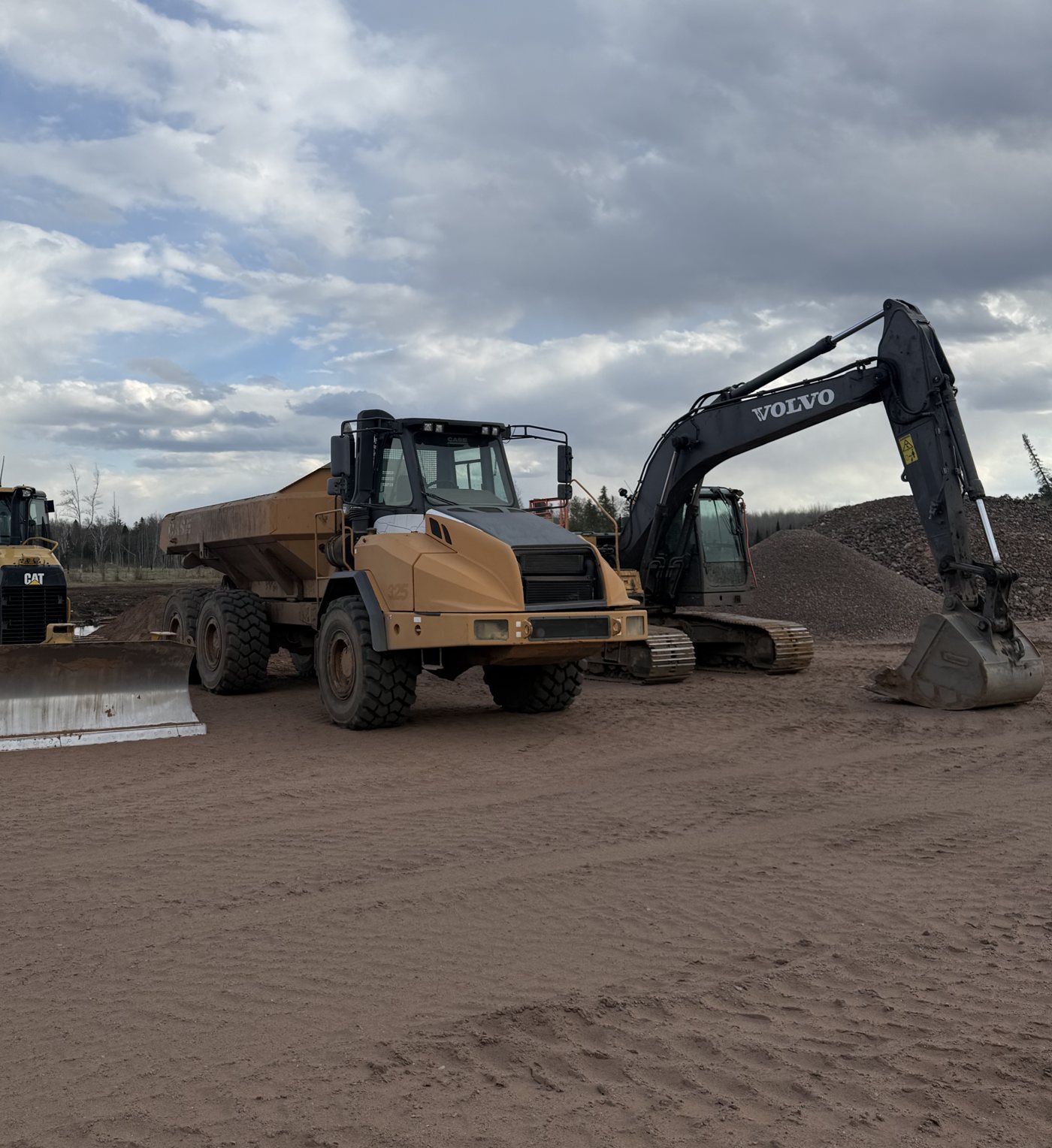 Dozer, articulated dump truck, and excavator lined up in the yard