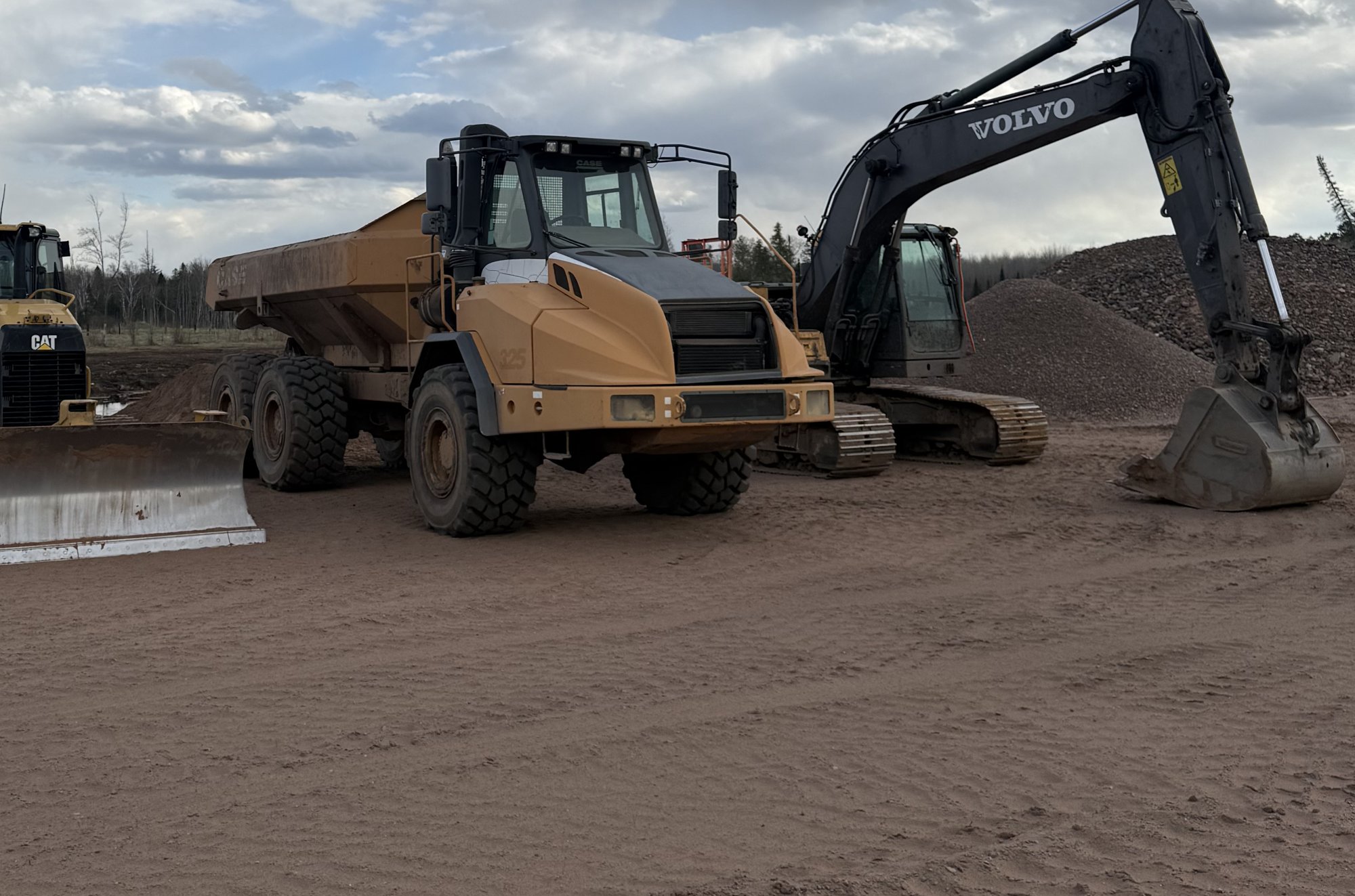 Cat dozer, Case articulated dump truck, and Volvo excavator lined up in the Joe Kimmes yard