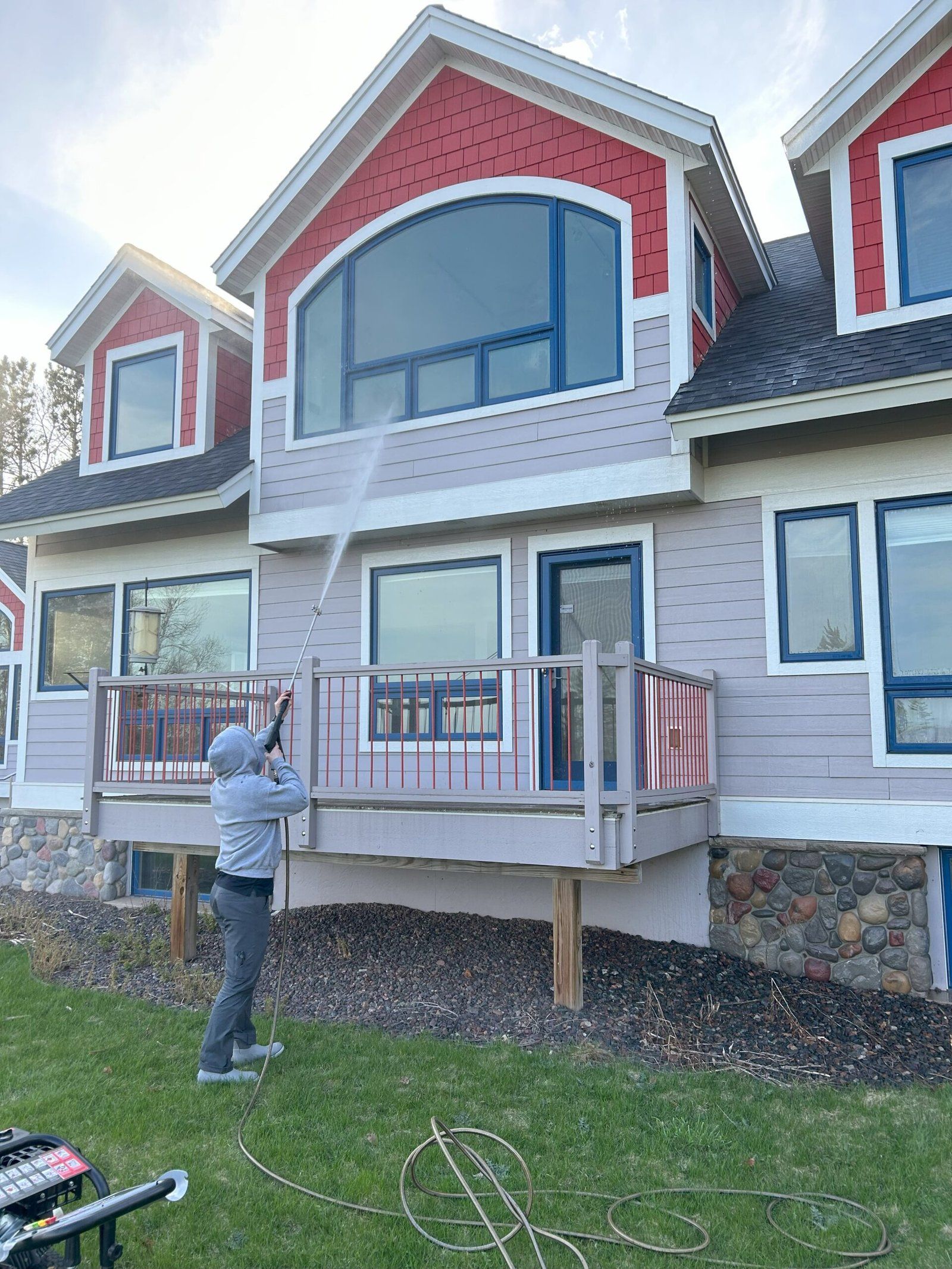 MC Pressure Washing technician soft-washing a two-story lakeside home