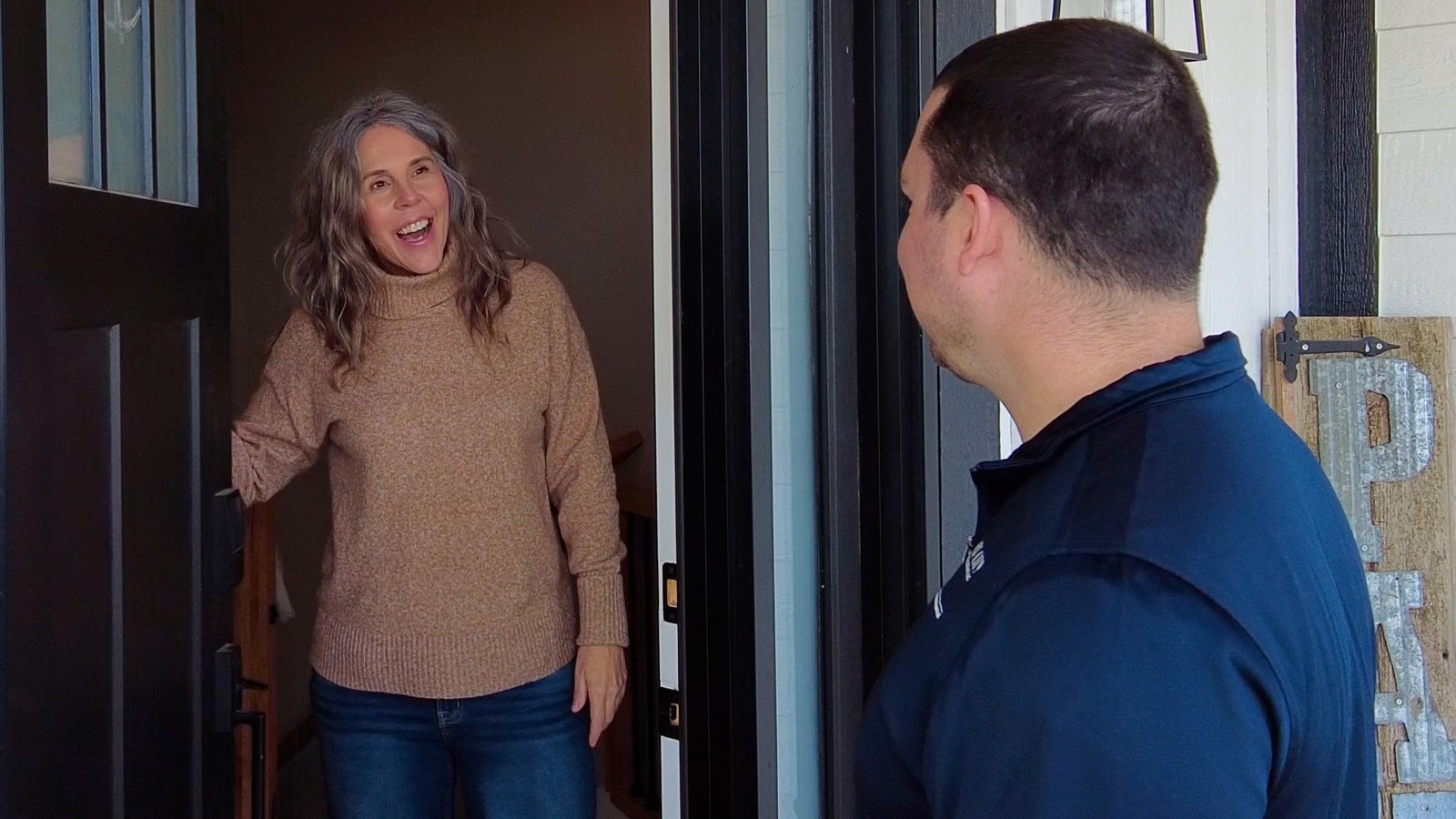 A River City technician greeting a smiling Omaha homeowner at her front door
