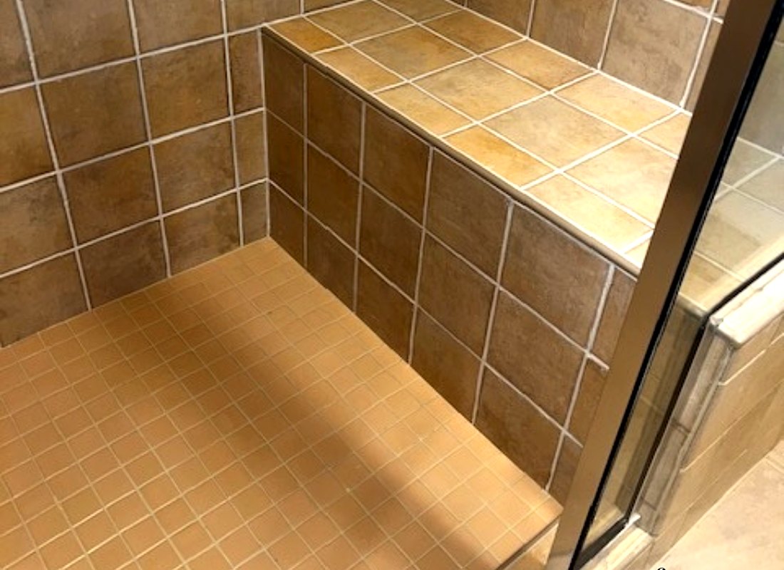 The same hotel shower after restoration, with clean tile, grout and bench