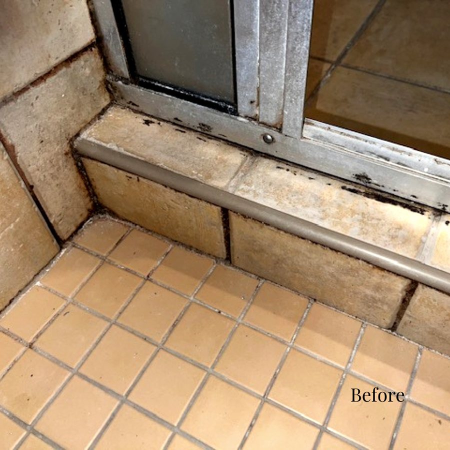 A shower door track with mildew and failed caulk