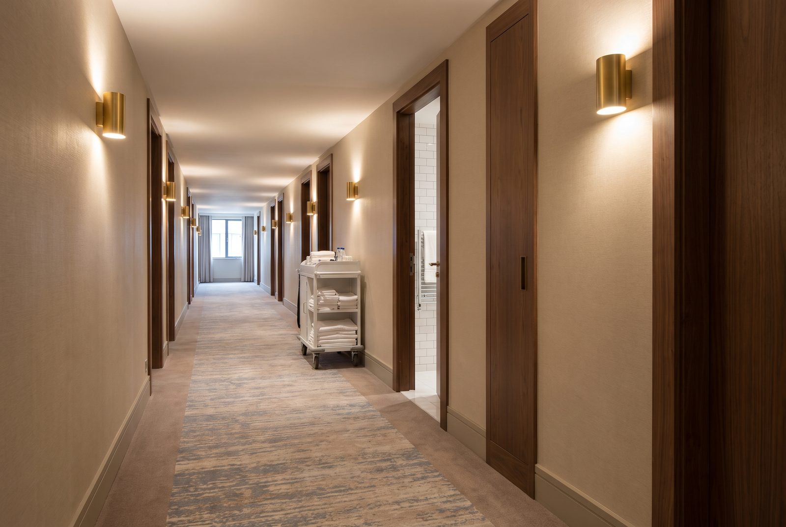 A hotel guest room corridor with a housekeeping cart
