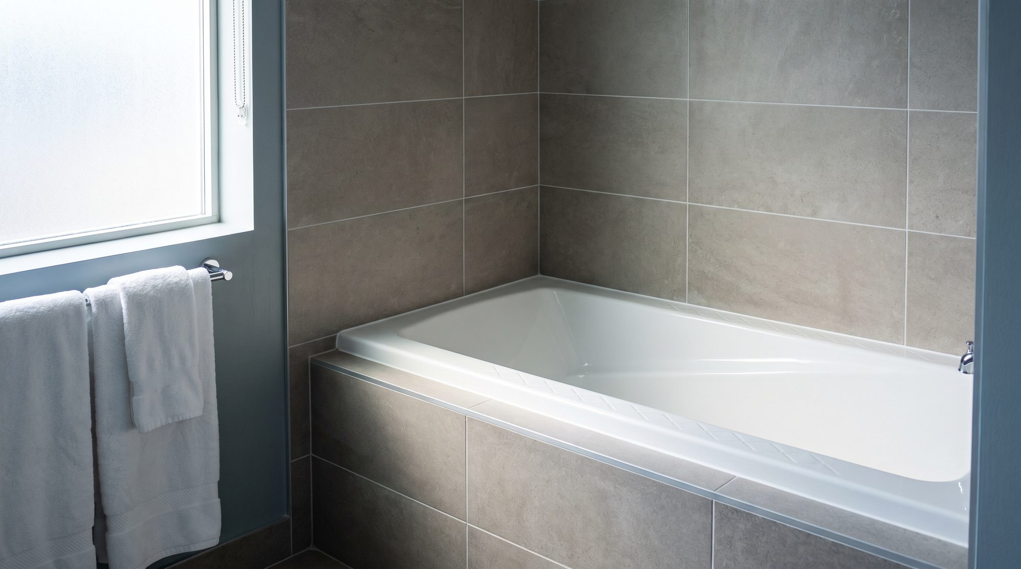 A refinished hotel guest bathtub with a diamond anti-slip tread, in a tiled hotel bathroom