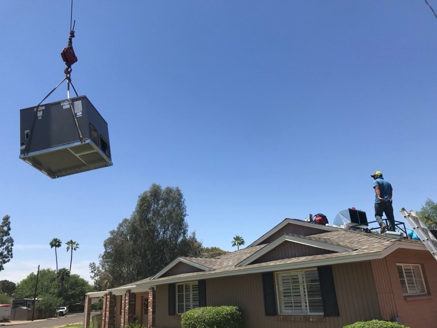 Crane lifting a rooftop HVAC unit over a Phoenix home