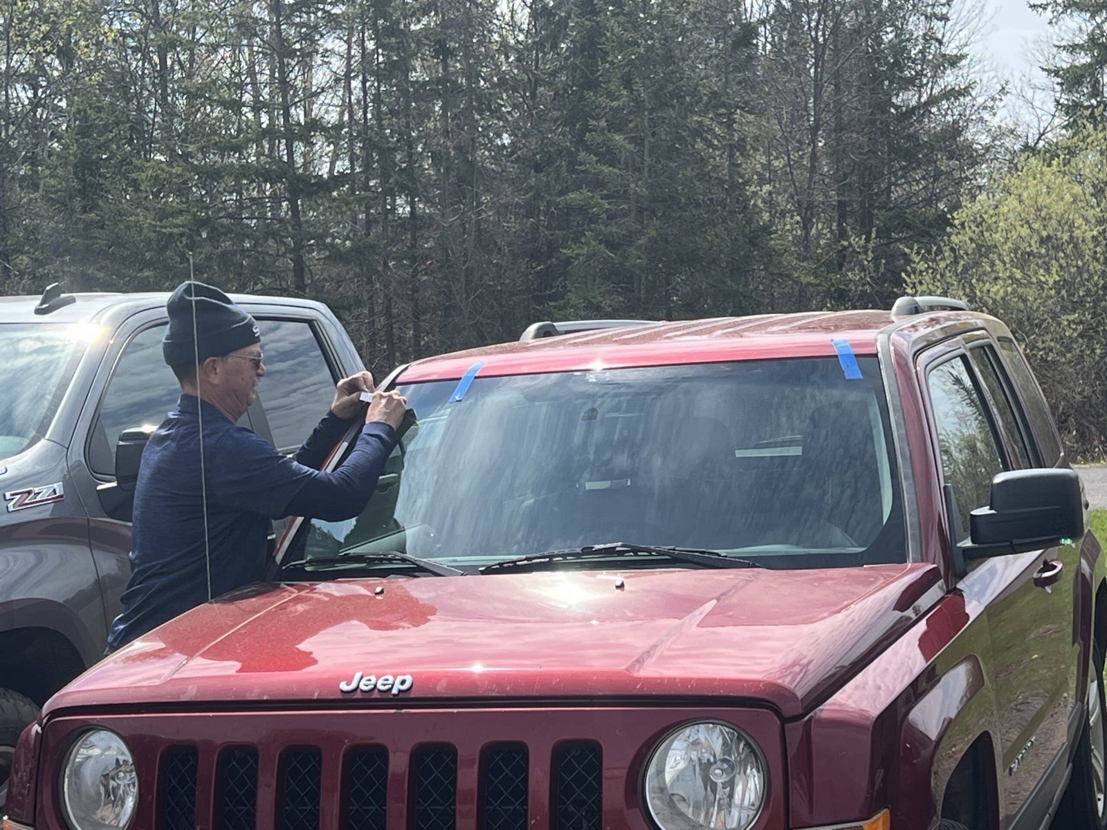 SGI Auto Glass technician setting a windshield on a Jeep at a customer's home