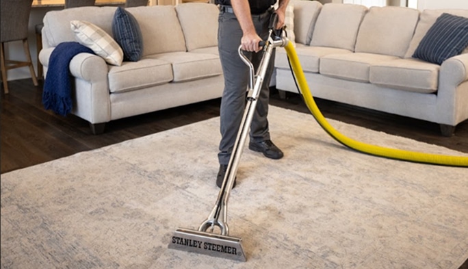 Stanley Steemer technician deep cleaning carpet