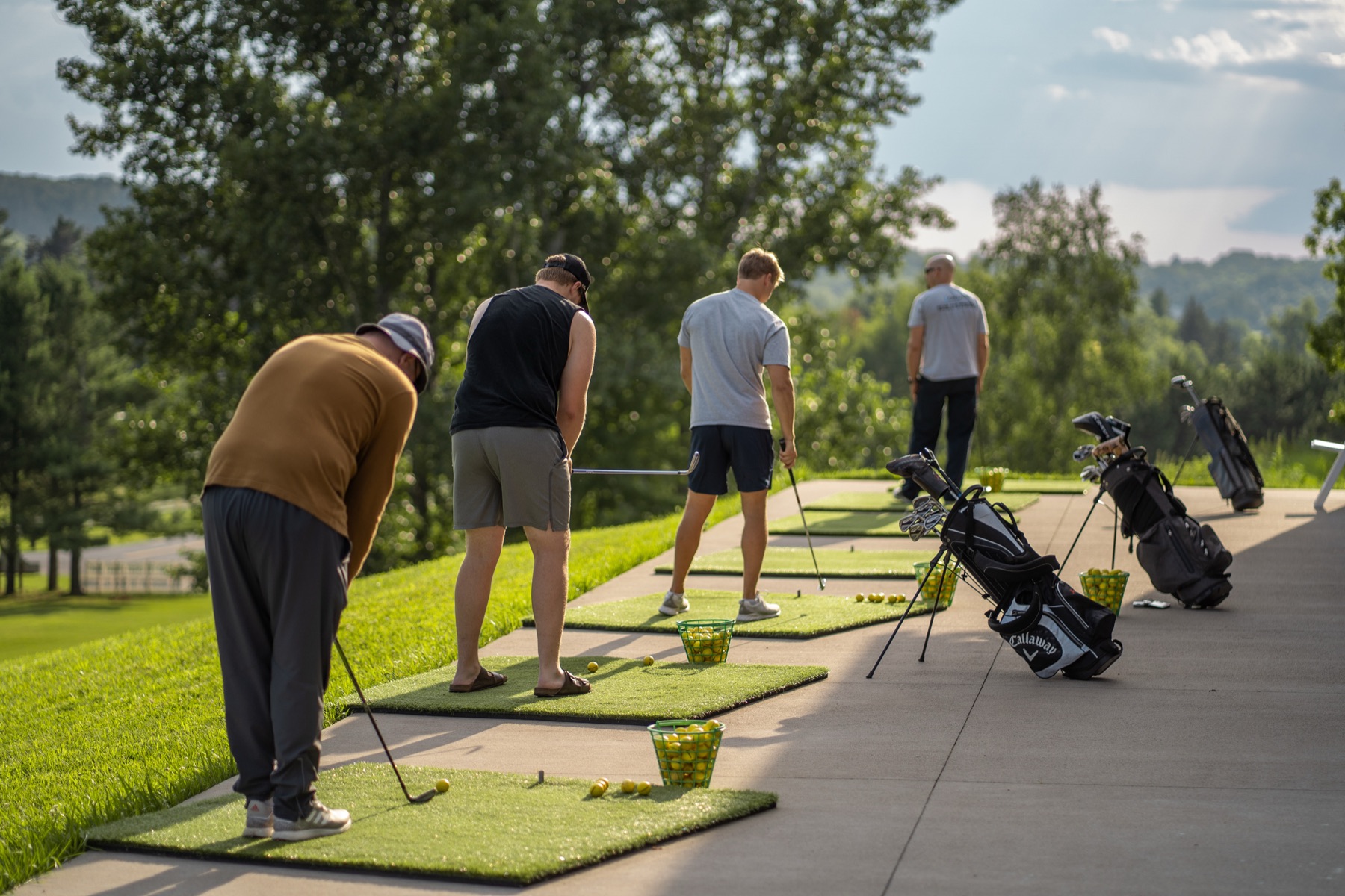 Golfers at the Tanglewood Greens Toptracer Range at golden hour